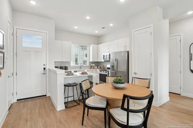 a kitchen with a dining table chairs refrigerator and cabinets