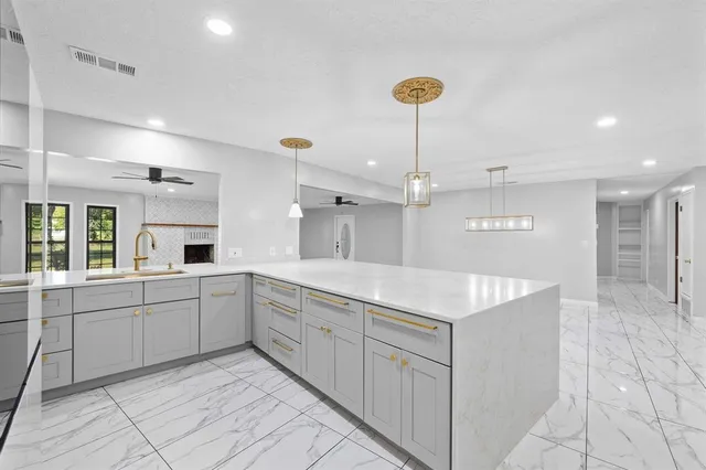 a large kitchen with kitchen island a sink a counter space and a refrigerator