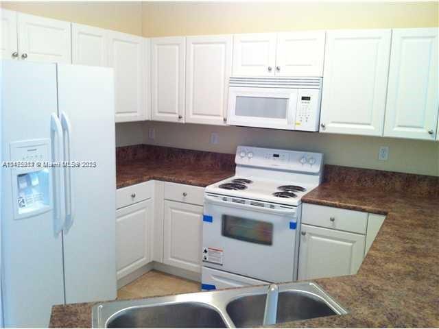 11459 Southwest 238th Street, Unit 11459 Homestead, FL 33032 - Photo 5 of 12 a kitchen with a stove refrigerator and cabinets