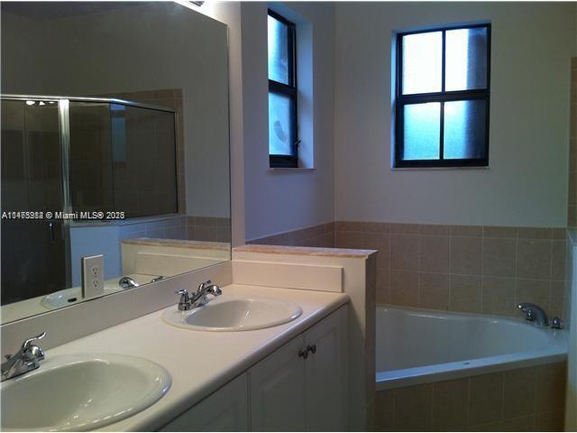11459 Southwest 238th Street, Unit 11459 Homestead, FL 33032 - Photo 7 of 12 a bathroom with a sink and a bathtub