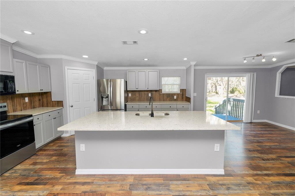 7405 Shoupe Road Plant City, FL 33565 - Photo 8 of 61 a large kitchen with stainless steel appliances a large counter top a stove a sink a refrigerator and a granite counter tops with white cabinets