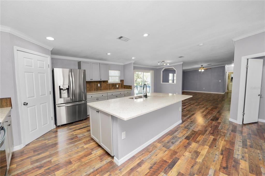 7405 Shoupe Road Plant City, FL 33565 - Photo 10 of 61 a large kitchen with a center island wooden floor stainless steel appliances and cabinets