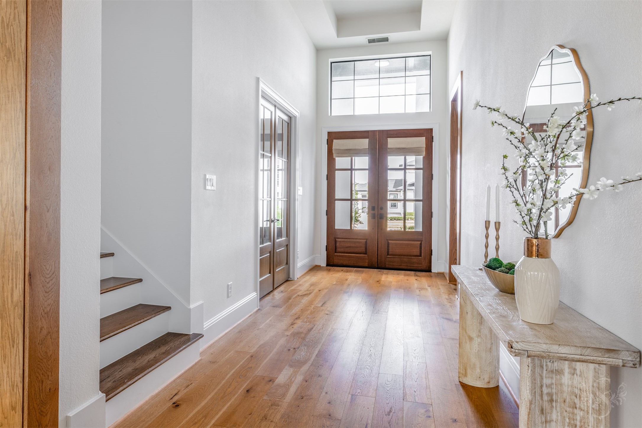 27919 Indigo Ridge Drive Fulshear, TX 77441 - Photo 7 of 50 The elegant entry welcomes you with warm wood floors, soaring ceilings, and abundant natural light streaming through the transom window and double front doors. French doors lead to the private study, while the wood staircase adds a refined touch to this inviting first impression.