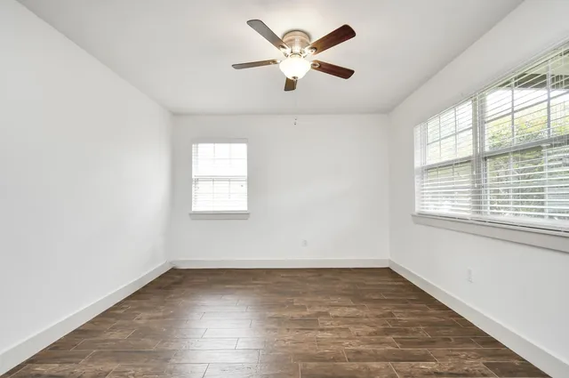 an empty room with wooden floor and windows
