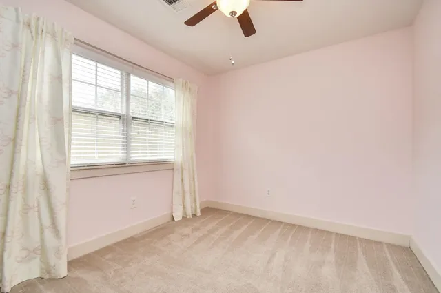 an empty room with ceiling fan and window