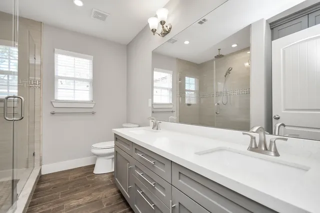 a bathroom with a sink double vanity granite and a toilet
