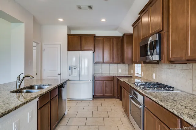a kitchen with stainless steel appliances granite countertop a sink stove and refrigerator