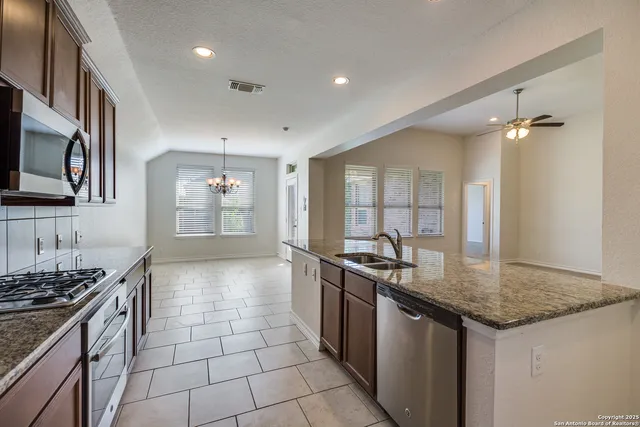 a kitchen with stainless steel appliances granite countertop a sink stove and cabinets
