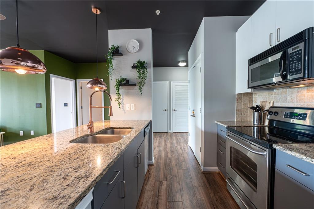 898 Oak Street Southwest, Unit 1410 Atlanta, GA 30310 - Photo 8 of 31 a kitchen with stainless steel appliances granite countertop a sink a stove top oven and wooden floor
