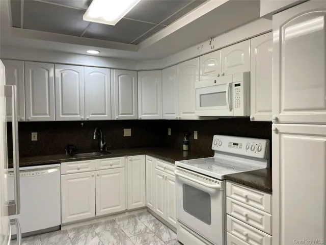 a kitchen with white cabinets and sink