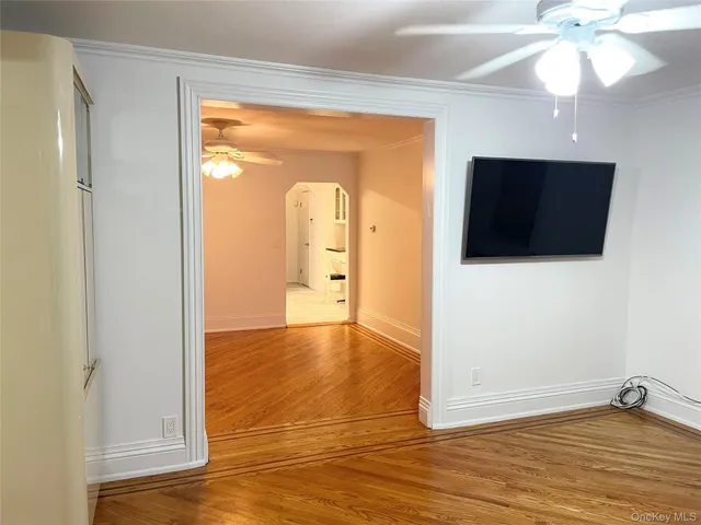 a view of empty room with wooden floor and fan