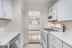 a kitchen with white cabinets and appliances