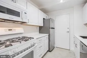 a kitchen with stainless steel appliances granite countertop white cabinets and a stove a oven with white countertops