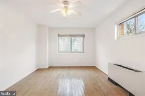 an empty room with wooden floor chandelier fan and windows