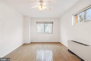 3900 Tunlaw Road Northwest, Unit 305 Washington, DC 20007 - Photo 23 of 32 an empty room with wooden floor chandelier fan and windows