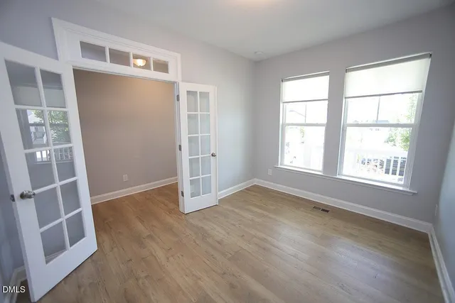 an empty room with wooden floor and windows