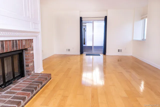 a view of empty room with wooden floor and fireplace