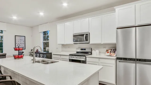 a kitchen with a refrigerator a stove and white cabinets