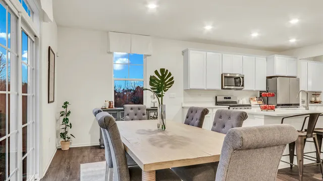 a view of kitchen with microwave stove refrigerator dining table and chairs