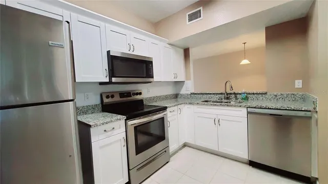 a kitchen with granite countertop a stove sink and refrigerator