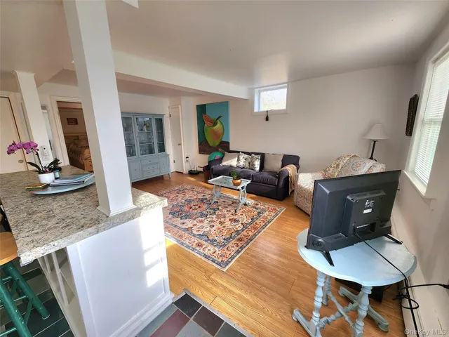 a living room with stainless steel appliances kitchen island granite countertop furniture and a wooden floor