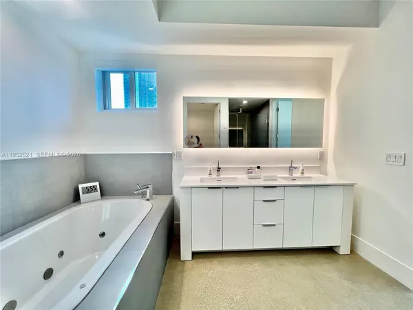 a bathroom with a double vanity sink mirror and bathtub