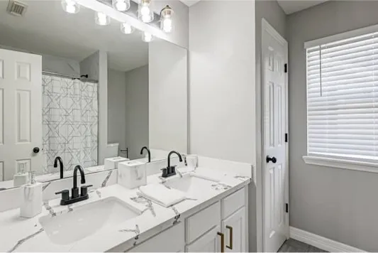 a bathroom with double vanity sinks and a mirror