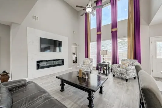 a living room with furniture a flat screen tv and a large window