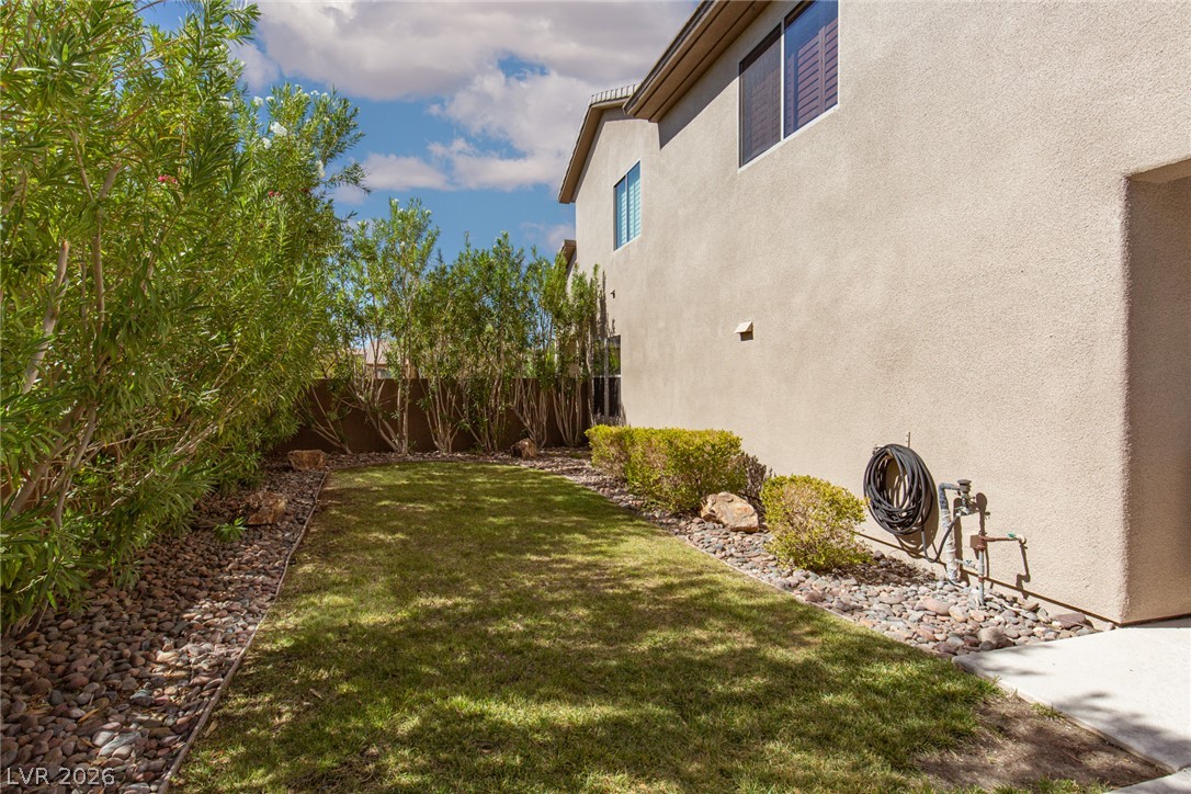 22 Douglas Grove Road Henderson, NV 89052 - Photo 67 of 72 A well-maintained side yard features verdant grass, a stone perimeter, and privacy plantings against the residence.