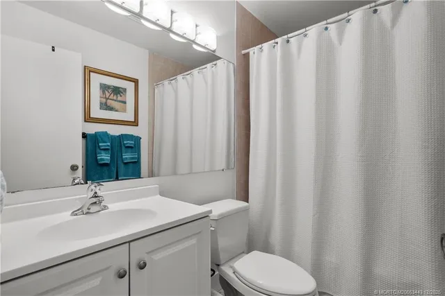 a bathroom with a sink a toilet a mirror and shower curtain
