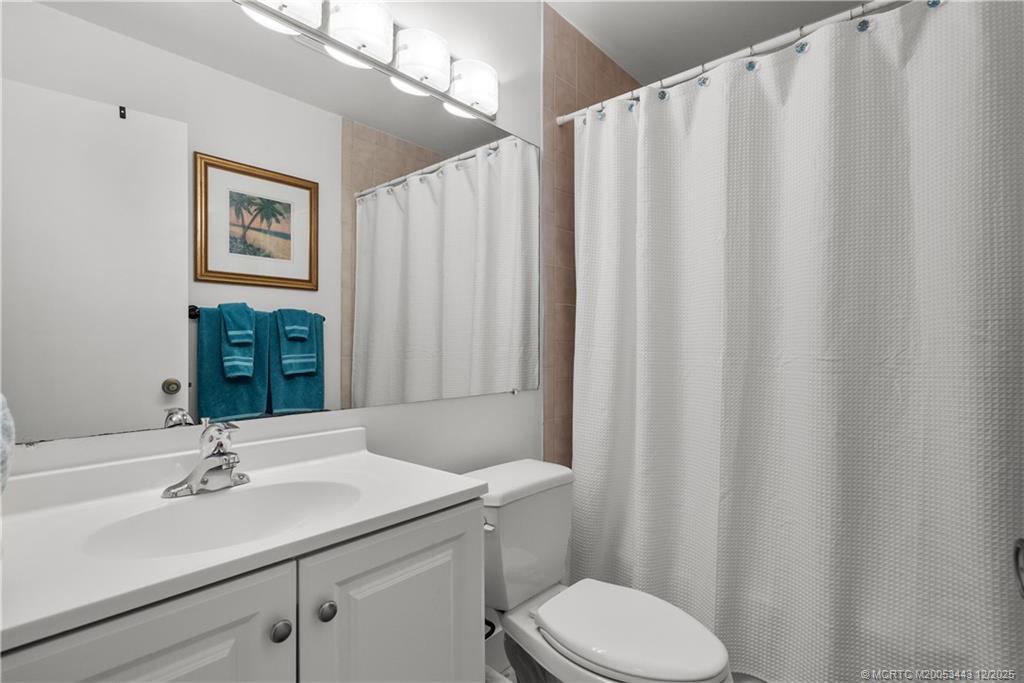 1544 Southwest Silver Pine Way, Unit 104F Palm City, FL 34990 - Photo 18 of 49 a bathroom with a sink a toilet a mirror and shower curtain