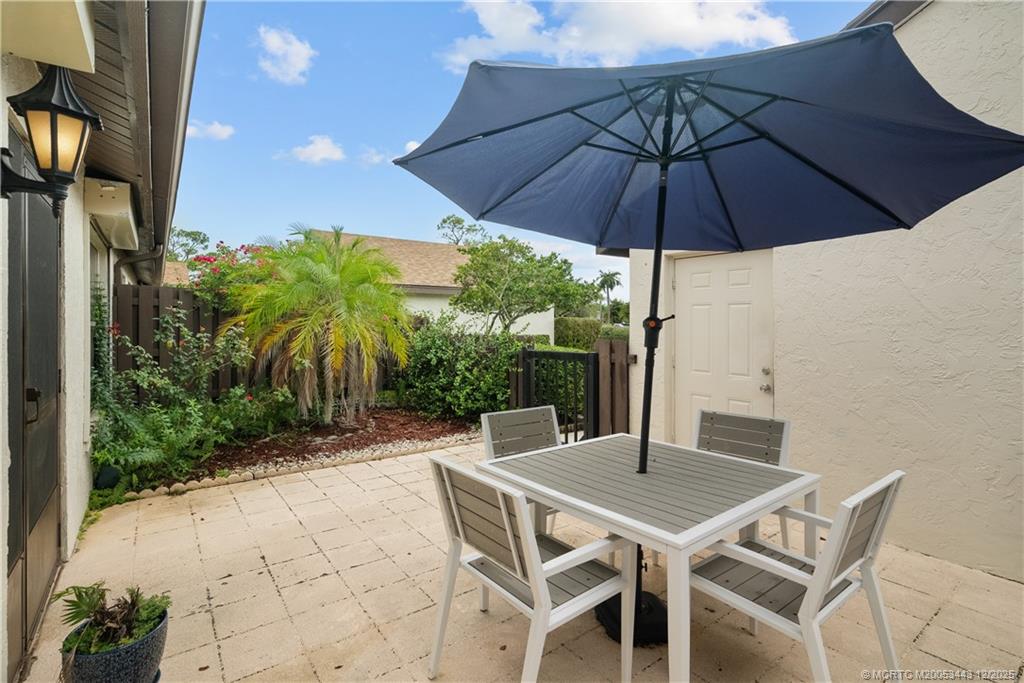 1544 Southwest Silver Pine Way, Unit 104F Palm City, FL 34990 - Photo 8 of 49 a patio with a table and chairs under an umbrella
