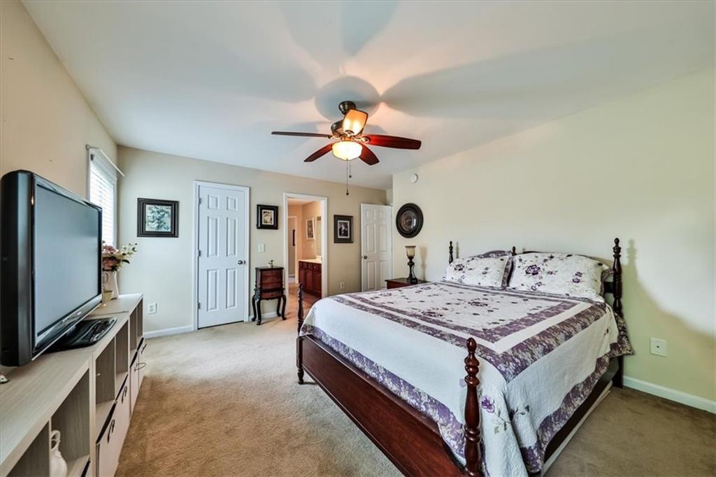 176 Oakland Way Dallas, GA 30157 - Photo 38 of 74 a spacious bedroom with a bed and a flat screen tv