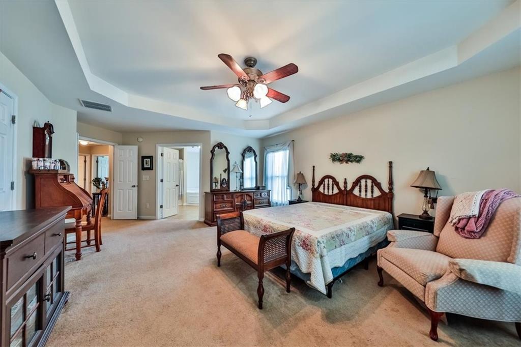 176 Oakland Way Dallas, GA 30157 - Photo 41 of 74 a spacious bedroom with a bed and a chandelier