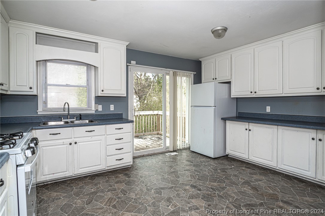 214 Lansdowne Road Fayetteville, NC 28314 - Photo 7 of 22 a kitchen with granite countertop white cabinets white appliances a sink and a window
