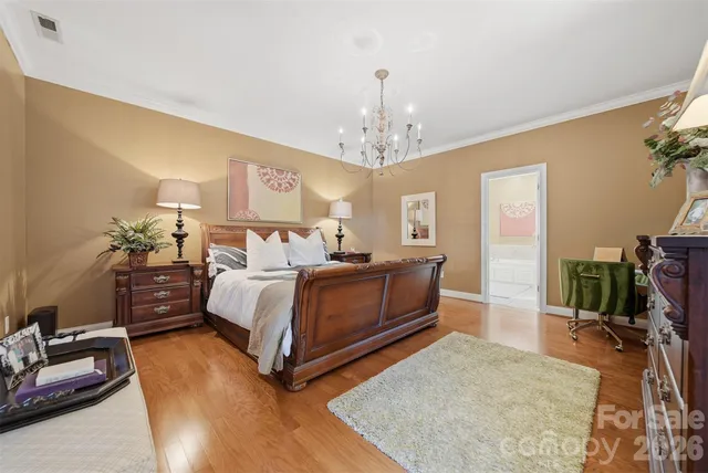 a spacious bedroom with a bed and dresser with wooden floor