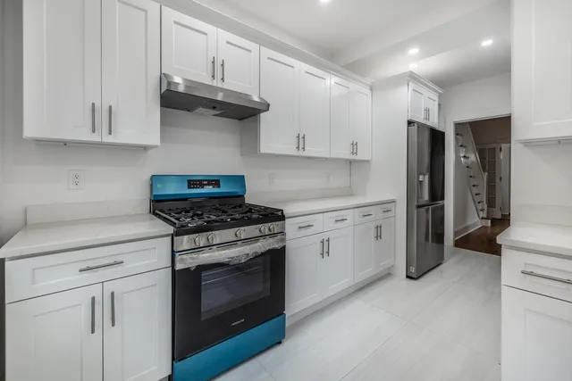 a kitchen with stainless steel appliances granite countertop a stove a refrigerator and a white cabinets