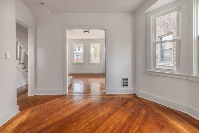 an empty room with wooden floor and windows