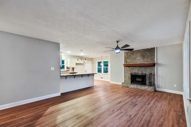a view of an empty room with wooden floor fireplace and a window