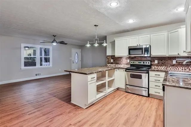 a kitchen with granite countertop a stove top oven microwave and cabinets