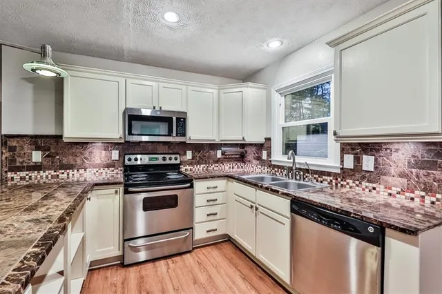 a kitchen with stainless steel appliances granite countertop a sink stove and cabinets