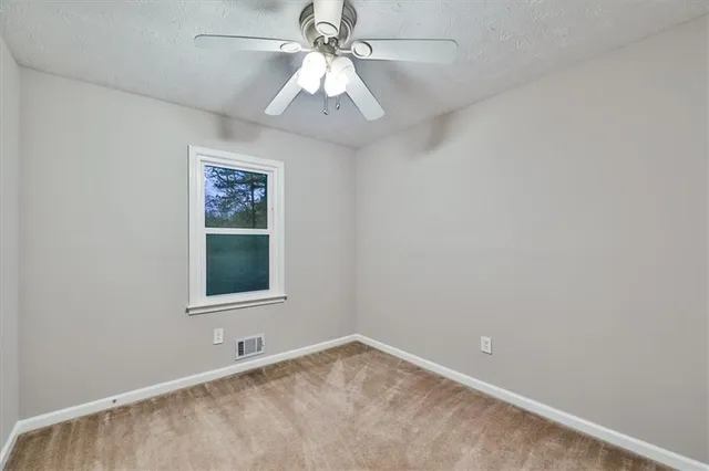 an empty room with windows and fan