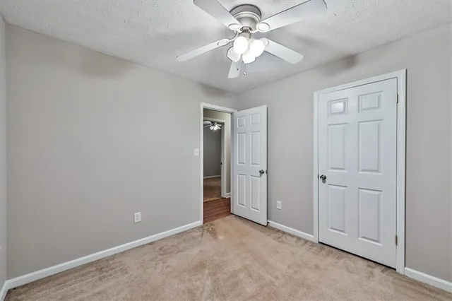 an empty room with a chandelier fan and closet area