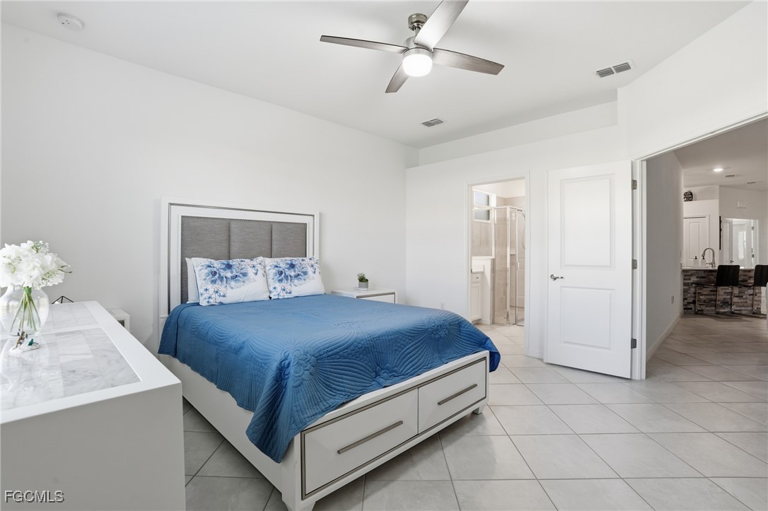 2617 Vine Avenue Naples, FL 34120 - Photo 16 of 27 a bedroom with a bed and a chandelier