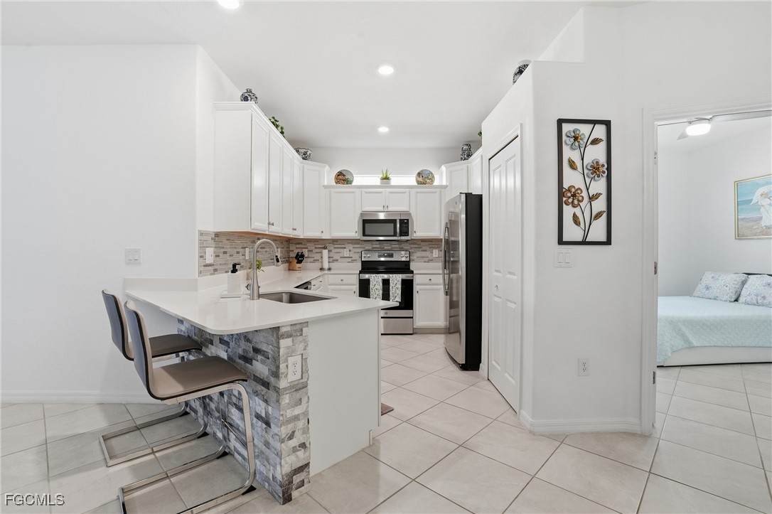 2617 Vine Avenue Naples, FL 34120 - Photo 3 of 27 a kitchen with stainless steel appliances kitchen island granite countertop a refrigerator and a stove top oven