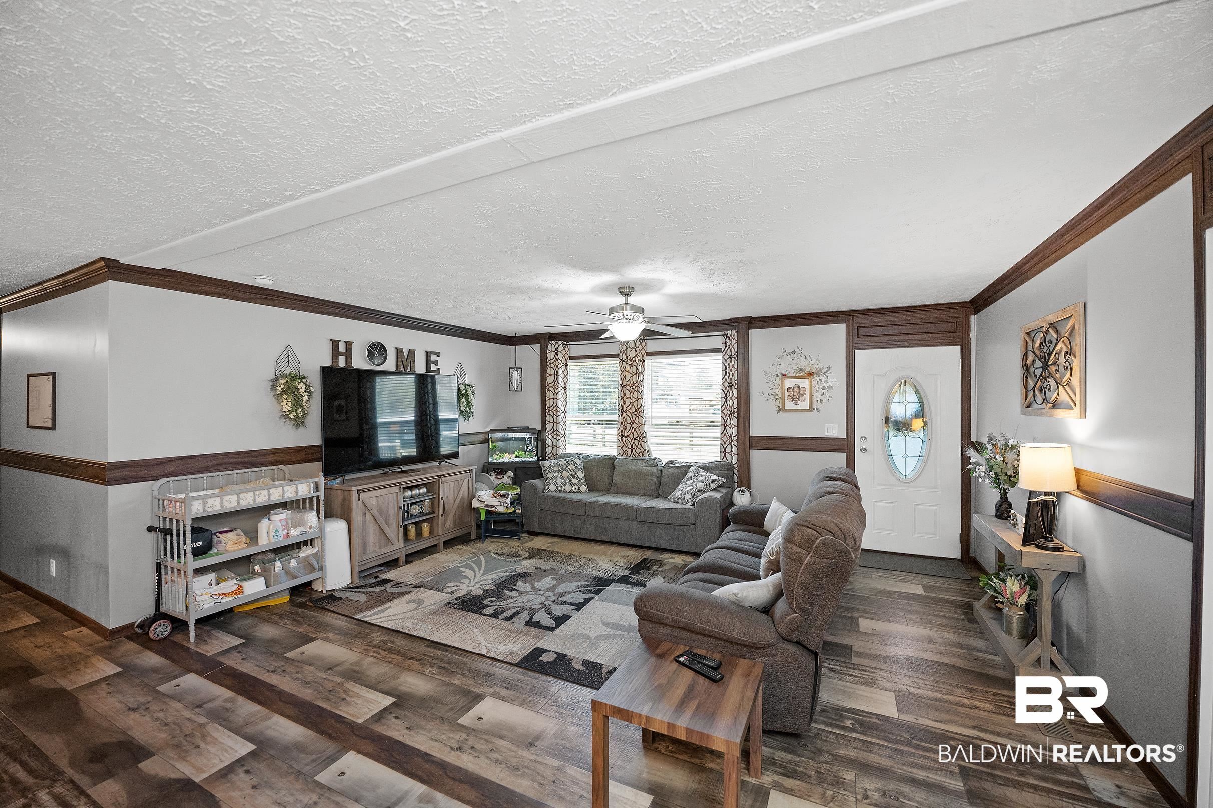 8630 Allison Lane Wilmer, AL 36587 - Photo 7 of 31 Living room with a textured ceiling, crown molding, dark wood-type flooring, and a ceiling fan