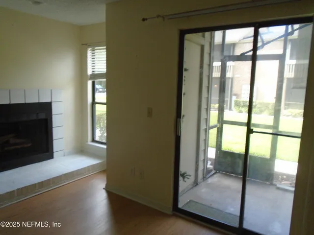 a view of an empty room with wooden floor and a fireplace