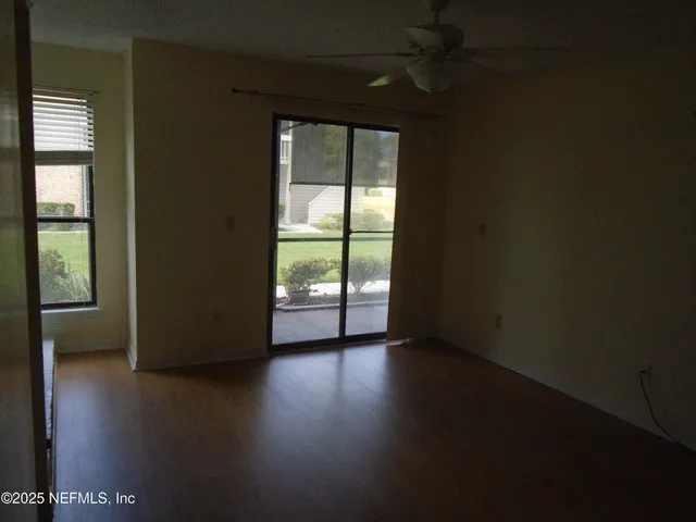 an empty room with wooden floor and windows