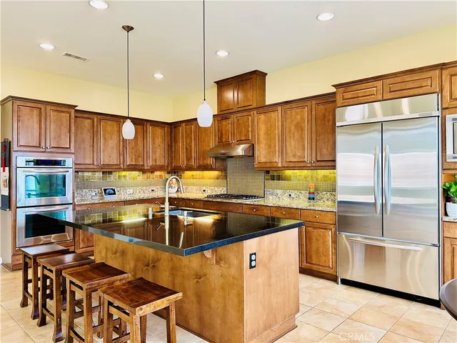 a kitchen with stainless steel appliances granite countertop a sink a stove and a refrigerator
