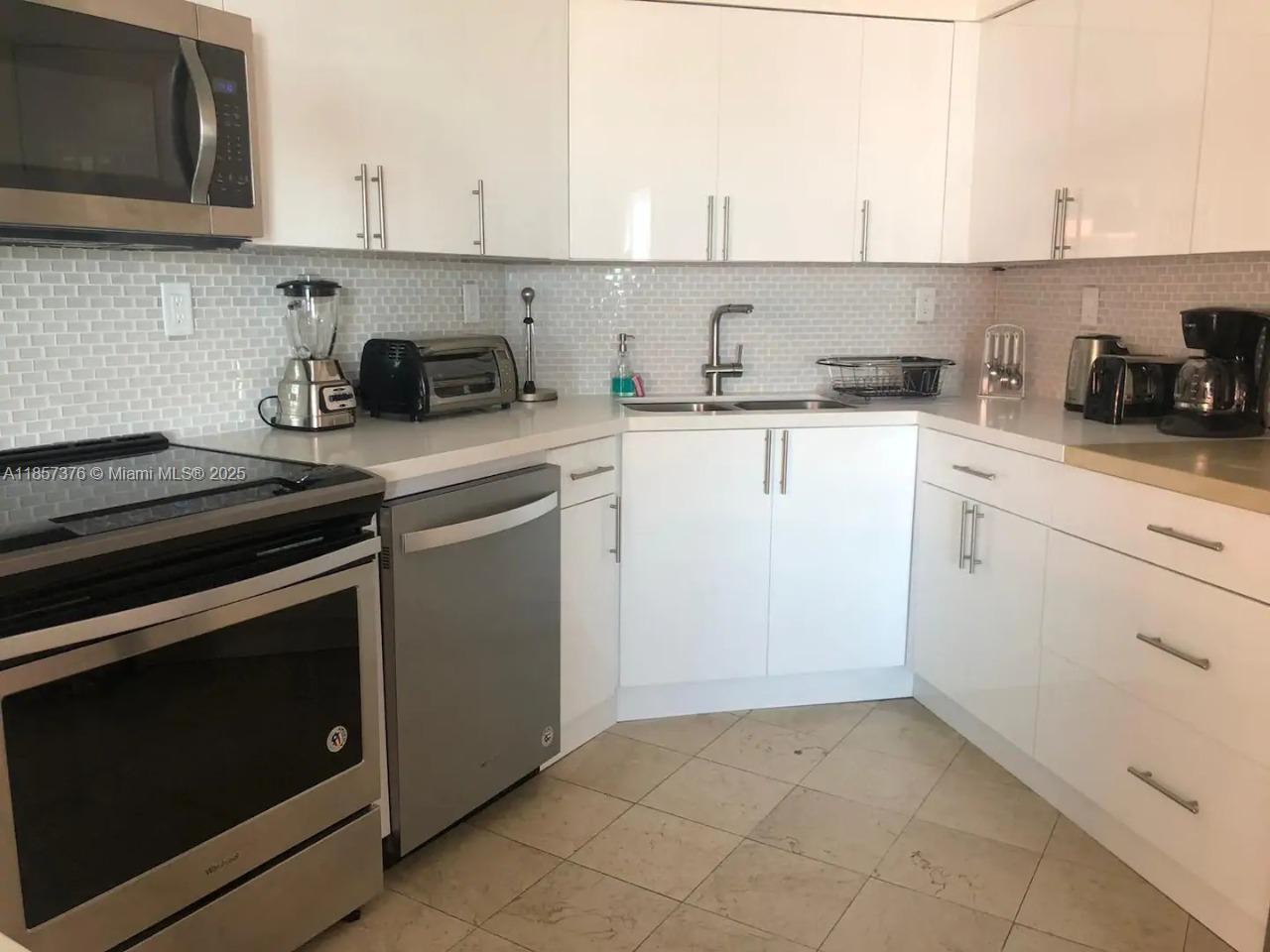 5161 Collins Avenue, Unit 1104 Miami Beach, FL 33140 - Photo 6 of 19 a kitchen with cabinets appliances and a sink